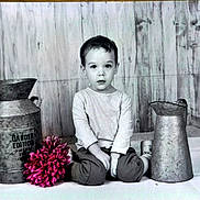 Naël participe au concours pour gagner de l'argent avec cette photo : casual_clothing, child, curious, decor, floor, flower, indoors, innocence, jug, metal_container, monochrome, pink_flower, portrait, pot, rustic, sitting, studio, vintage, wooden_background, young_boy