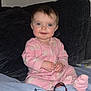 baby, child, pajamas, pink_clothing, sitting, bed, couch, indoor, face, smile, blue_eyes, blanket, headband, person, infant, cozy, furniture, home, cute, portrait