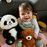 baby, blanket, child, clothing, couch, cute, face, happy, head, home, indoor, infant, panda_toy, person, plush_toy, sitting, smiling, striped_socks, teddy_bear, toy
