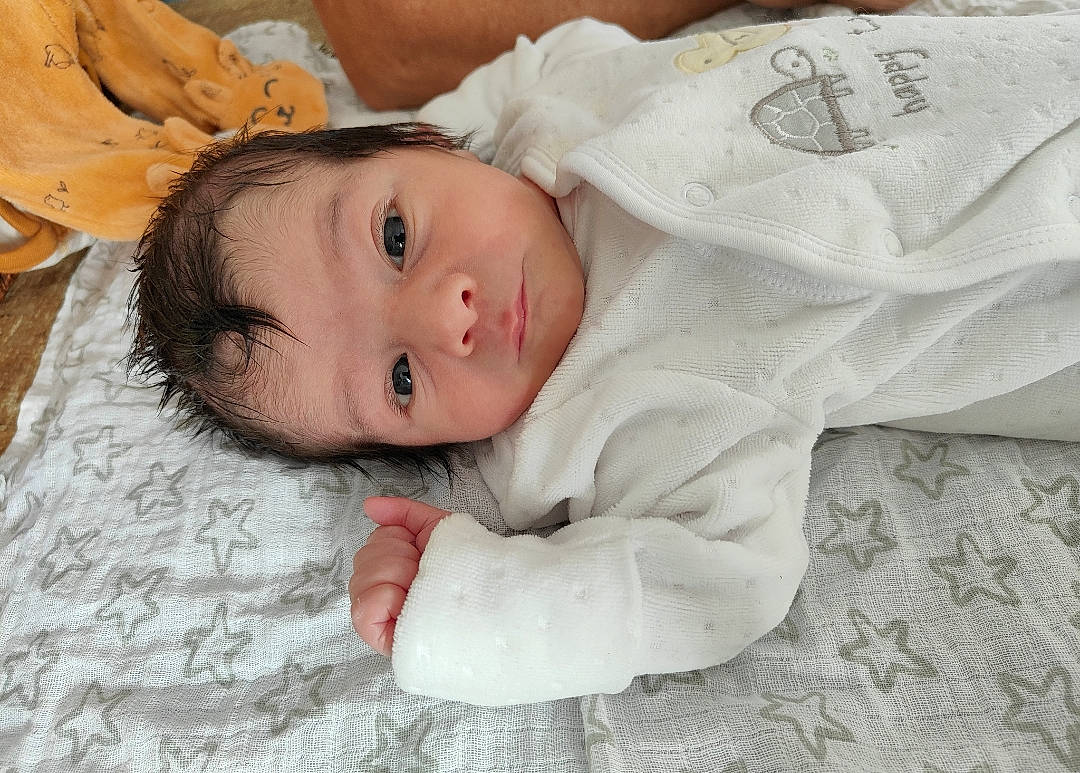 Hélyo participe au concours pour gagner de l'argent avec cette photo : baby, baby_toddler_clothing, cheek, child, comfort, eye, flooring, fur, grass, happy, iris, linens, nose, person, portrait_photography, room, sitting, skin, sleeve, toddler