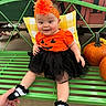 Avalynn is registered to the contest to win money with this photo: baby, child, infant, smiling, halloween, pumpkin, costume, orange_shirt, black_skirt, tutu, flower_headband, headband, socks, green_chair, outdoor, portrait, seated, fashion, festive, jack_o_lantern