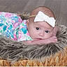 baby, basket, bow, child, curious, cute, expression, eyes, floor, floral_dress, fur, hands, headband, indoors, infant, lying_down, newborn, portrait, skin, soft_texture