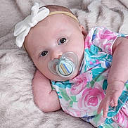 Mackenzie joined the competition — help win amazing prizes! baby, infant, pacifier, headband, white_bow, floral_outfit, colorful_clothing, soft_blanket, fur_texture, lying_down, cute, portrait, indoors, child, newborn, skin, hand, face, eyes, baby_girl