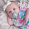 baby, baby_girl, child, colorful_clothing, cute, eyes, face, floral_outfit, fur_texture, hand, headband, indoors, infant, lying_down, newborn, pacifier, portrait, skin, soft_blanket, white_bow