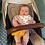 Sofia is registered to the contest to win money with this photo: baby, stroller, pink_clothing, bib, yellow_toy, indoor, floor_tiles, cabinet, face, hands, feet, polka_dot, knitted, child, infant, seated, comfort, home, cute, portrait