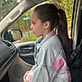 child, girl, car_interior, denim_jacket, ponytail, side_profile, passenger_seat, window, nature_outside, road_sign, seatbelt, long_hair, casual_clothing, daylight, forest, vehicle, seat, young, portrait, sitting