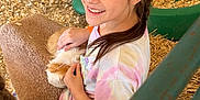 Aleigha joined the competition — help win amazing prizes! child, girl, petting, guinea_pig, animal, hay, straw, cage, green_container, smile, braid, casual_clothing, indoor, animal_enclosure, happy, person, young, pet, playful, brown_hair