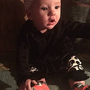 Aleigha joined the competition — help win amazing prizes! baby, child, indoor, black_clothing, headband, bow, patterned_leggings, orange_socks, carpet, curious_expression, sitting, hand, face, person, infant, young_child, cute, looking_away, cozy, dim_lighting