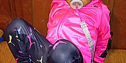 Ahna is registered to the contest to win money with this photo: toddler, child, pacifier, hair_bows, pink_jacket, colorful_clothing, sneakers, sitting, wicker_bench, wooden_wall, curious_expression, indoor, casual_pose, fashion, young_child, person, cute, playful, bright_colors, comfortable