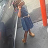 child, girl, sunglasses, braids, hair_beads, denim_dress, dress, sandals, standing, posing, outdoor, parking_lot, car, vehicle, orange_bollard, sidewalk, driveway, sunlight, fashion, portrait