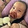 Mariah is registered to the contest to win money with this photo: baby, pacifier, plush_toy, sheep, pink_cushion, close_up, infant, child, soft_toy, cozy, cute, clothing, hand, face, seatbelt, indoors, portrait, young_child, smiling, curious
