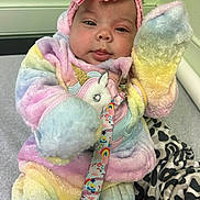 Mariah joined the competition — help win amazing prizes! baby, child, unicorn, onesie, plush, rainbow, headband, pink_bow, patterned_blanket, indoor, cute, face, hand, sitting, soft_toys, clothing, person, infant, warm, colorful