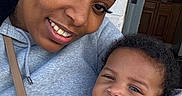 Princess is registered to the contest to win money with this photo: woman, baby, child, smile, face, portrait, headband, earrings, sweatshirt, blanket, doorway, cabinet, indoor, hug, closeup, skin, hair, clothing, person, happy