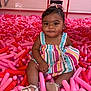 Araiya Lynn is registered to the contest to win money with this photo: toddler, child, baby, balloons, pink, red, dress, striped_clothing, sandals, indoor, play_area, playground, toy, colorful, smiling, cute, person, hair_bow, sitting, floor