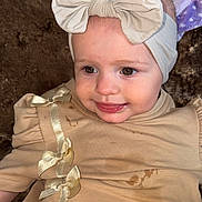 Mila joined the competition — help win amazing prizes! baby, infant, headband, bow, dress, beige, smiling, tongue, face, cute, child, young, stain, fabric, soft, clothing, sitting, person, portrait, indoors
