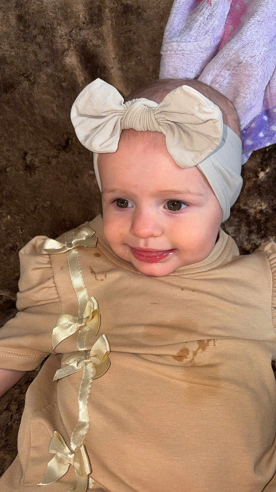 Mila joined the competition — help win amazing prizes! baby, infant, headband, bow, dress, beige, smiling, tongue, face, cute, child, young, stain, fabric, soft, clothing, sitting, person, portrait, indoors