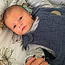 Ezio a rejoint le concours — aidez-le/la à gagner de superbes lots ! baby, infant, hand, ring, pacifier, blanket, cushion, pattern, clothing, blue, gray, person, skin, face, eyes, lying_down, indoor, newborn, comfort, calm