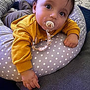 Chaieb Noah a rejoint le concours — aidez-le/la à gagner de superbes lots ! baby, pacifier, yellow_sweater, polka_dot, cushion, indoor, carpet, hand, face, child, curious, laying_down, clothing, comfort, young_child, person, soft_furniture, home, baby_accessory, portrait