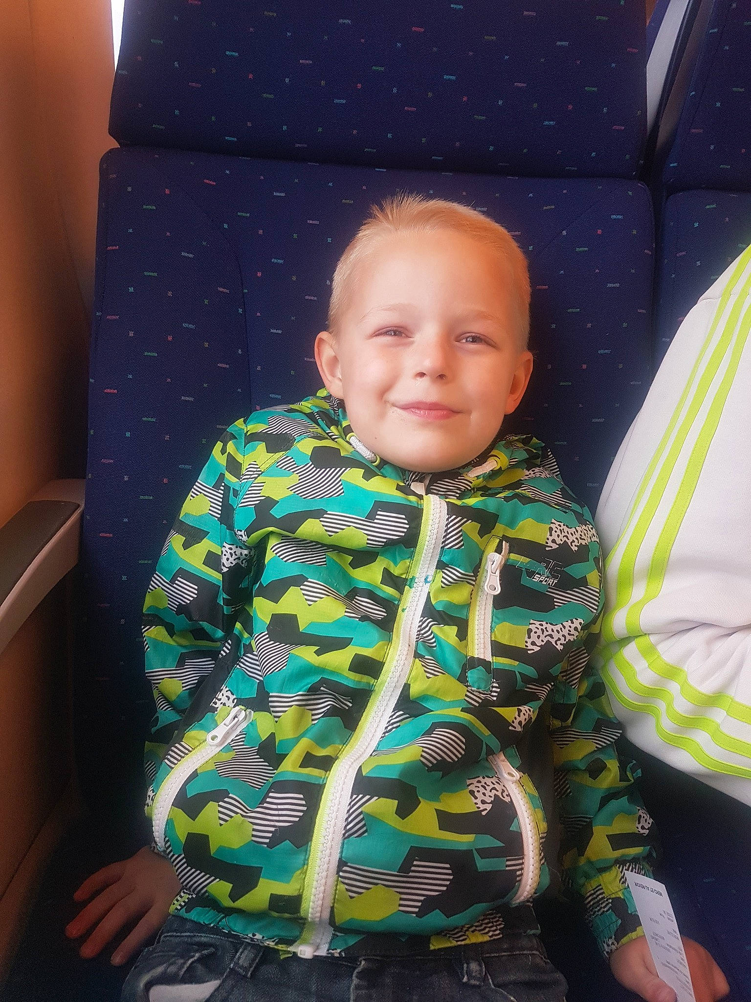 Theo a rejoint le concours — aidez-le/la à gagner de superbes lots ! baby, baby_products, car_seat, cheek, child, face, fun, green, head, outerwear, pattern, person, play, sitting, skin, smile, toddler, vacation