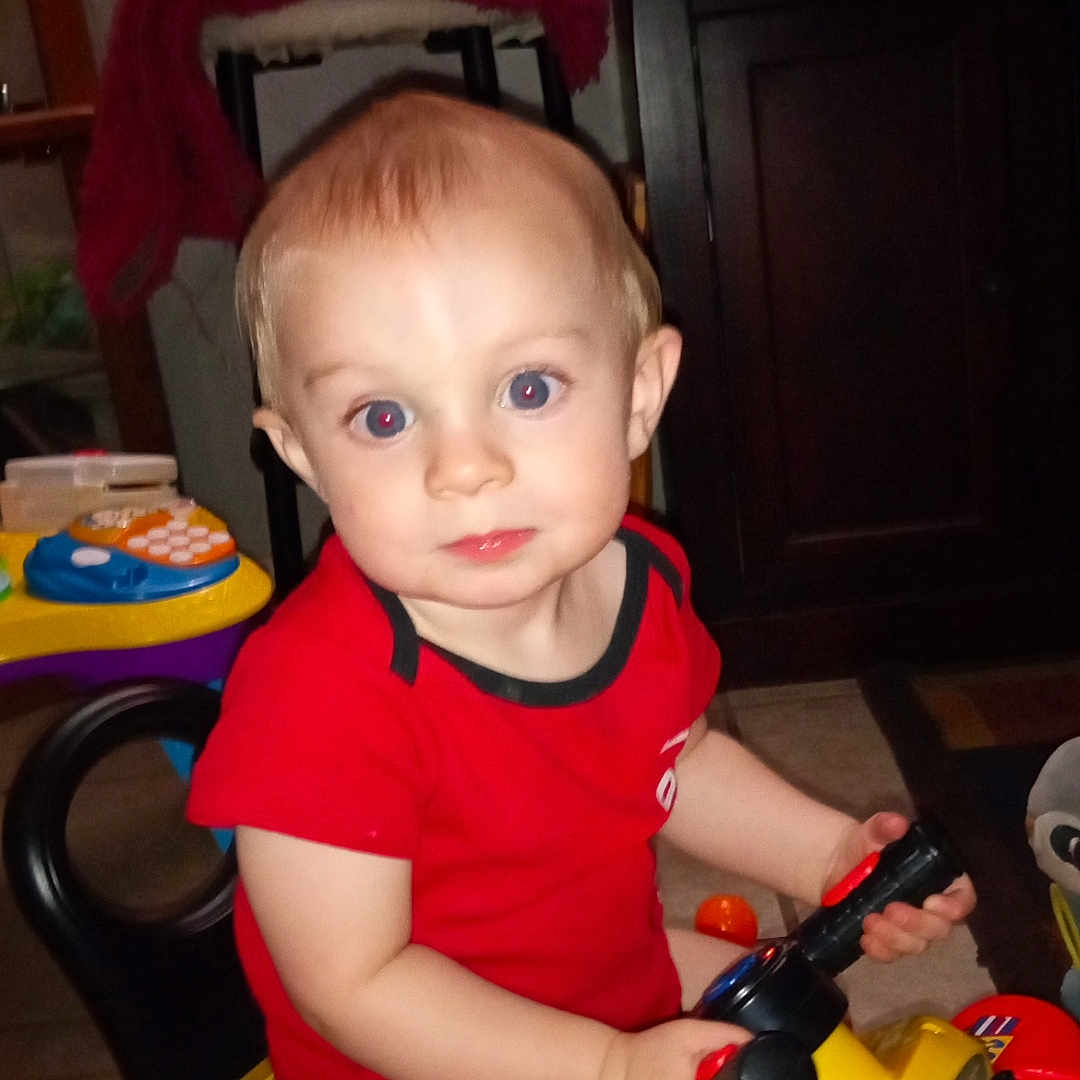 Jordan is registered to the contest to win money with this photo: baby, bathroom, bodypart, clothing, face, finger, hand, head, indoors, person, photography, portrait, room, sitting, t_shirt, toilet, toy, transportation, tricycle, vehicle