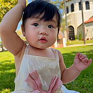Cathlina joined the competition — help win amazing prizes! baby, child, dress, pink_bow, outdoor, grass, sunny, park, blanket, curious, raising_hand, face, person, young_child, daylight, smiling, cute, portrait, nature, building