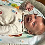 baby, blue_eyes, child, colorful, comfortable, curious, cute, face, happy, indoor, infant, light_skin, lying_down, onesie, play_mat, reaching_hand, smiling, soft_toys, wood_floor, young