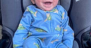 Andrew joined the competition — help win amazing prizes! baby, infant, car_seat, blue_onesie, turtle_print, smiling, happy, child, cute, young, sitting, clothing, fabric, seat, head, face, skin, person, child_seat, comfort