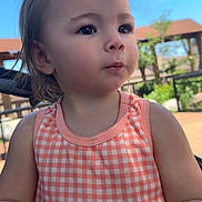 Kyla joined the competition — help win amazing prizes! toddler, child, outdoor, sunlight, dress, peach, checkered, hair, face, expression, snack, hand, curious, young_child, portrait, person, nature, blue_sky, daytime, casual
