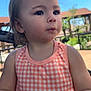 toddler, child, outdoor, sunlight, dress, peach, checkered, hair, face, expression, snack, hand, curious, young_child, portrait, person, nature, blue_sky, daytime, casual