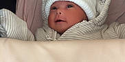 Ocean is registered to the contest to win money with this photo: baby, infant, hat, clothing, blanket, face, portrait, cute, smile, indoors, cozy, striped_clothing, white_hat, newborn, child, person, soft_toys_pattern, hood, warm, sleeping_bag