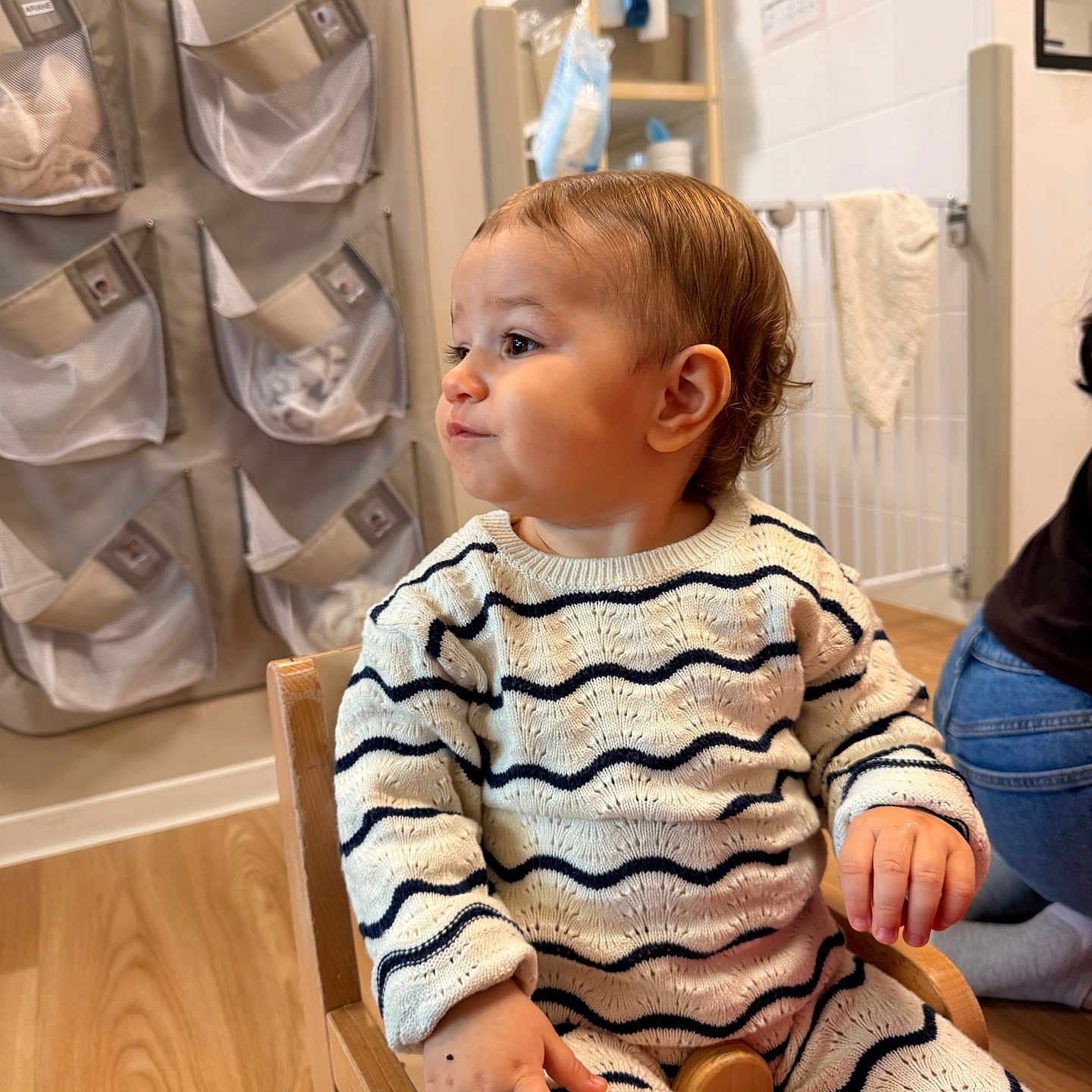 Mayana a rejoint le concours — aidez-le/la à gagner de superbes lots ! toddler, child, person, indoor, wooden_chair, knitwear, striped_clothing, flooring, storage_pockets, wall, curly_hair, seated, hand, face, expression, casual, home, baby, cute, clothing