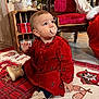 Mayana participe au concours pour gagner de l'argent avec cette photo : baby, child, pacifier, red_dress, christmas_tree_pattern, holiday_decor, rug, sitting, indoor, wooden_furniture, chair, boots, floor, curious, festive, cute, decorations, toy, warm_clothing, portrait