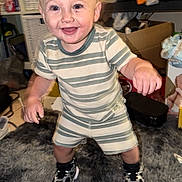 Beau joined the competition — help win amazing prizes! baby, blond_hair, box, child, face, furniture, happy, home, indoors, living_room, pajamas, portrait, rug, shelves, smiling, sneakers, standing, striped_clothing, toddler, toy