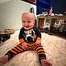Beau joined the competition — help win amazing prizes! baby, bedroom, child, face, furniture, halloween, happy, hat, household_items, indoor, mattress, orange_clothing, playful, portrait, pumpkin, sitting, skeleton_costume, smiling, striped_pants, television