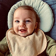 Elyo participe au concours pour gagner de l'argent avec cette photo : baby, bib, cheeks, closeup, cushion, eyes, green_clothing, hand, happy, head_support, infant, mouth, portrait, ribbed_shirt, seat, skin, smiling, soft_texture, teeth, toy
