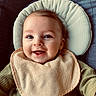 baby, bib, cheeks, closeup, cushion, eyes, green_clothing, hand, happy, head_support, infant, mouth, portrait, ribbed_shirt, seat, skin, smiling, soft_texture, teeth, toy