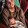 baby, infant, father, adult, sleeping, smiling, portrait, indoors, seated, holding, blanket, cushion, hoodie, beard, mustache, family, parenting, cuddling, cozy, photography