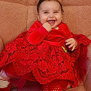 Ariel joined the competition — help win amazing prizes! baby, blanket, chair, child, cushion, eyes, face, family_photo, fashion, hair, hand, happy, indoor, infant, patterned_fabric, portrait, red_clothing, red_dress, sitting, smiling