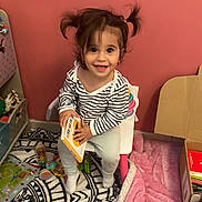 Masha a rejoint le concours — aidez-le/la à gagner de superbes lots ! toddler, child, book, chair, pigtails, toy, rug, blanket, indoor, smiling, striped_shirt, playroom, floor, cardboard_box, furniture, happy, person, cute, young_child, reading