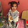 toddler, child, book, chair, pigtails, toy, rug, blanket, indoor, smiling, striped_shirt, playroom, floor, cardboard_box, furniture, happy, person, cute, young_child, reading