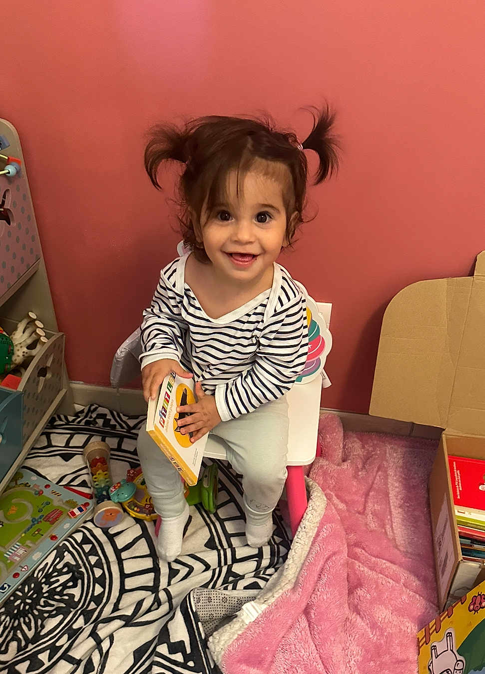 Masha a rejoint le concours — aidez-le/la à gagner de superbes lots ! toddler, child, book, chair, pigtails, toy, rug, blanket, indoor, smiling, striped_shirt, playroom, floor, cardboard_box, furniture, happy, person, cute, young_child, reading
