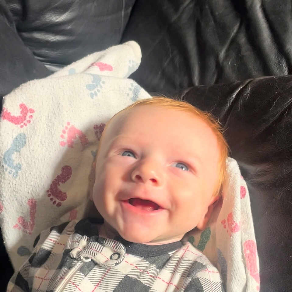 Leighton joined the competition — help win amazing prizes! baby, blanket, bodypart, clothing, couch, cushion, face, furniture, glove, happy, head, homedecor, laughing, mouth, newborn, person, photography, portrait, quilt, smile