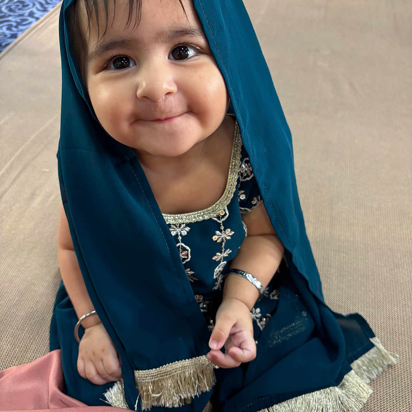 Kirat joined the competition — help win amazing prizes! baby, bracelet, child, cute, fabric, face, floor_mat, foot, gold_embroidery, hand, happy, indoor, playful_expression, portrait, sitting, smile, sparkling_eyes, teal_clothing, traditional_clothing, yellow_pants