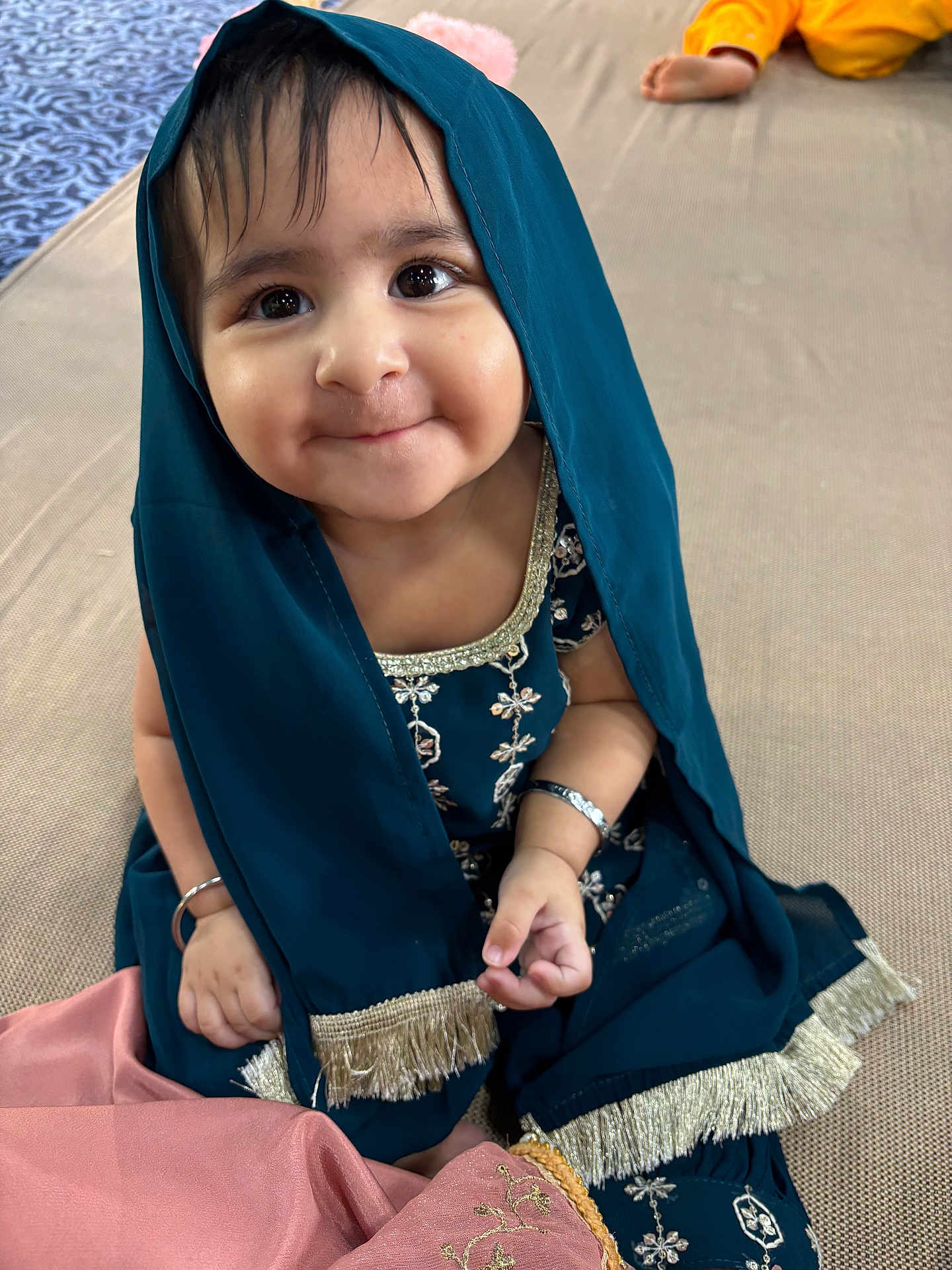 Kirat joined the competition — help win amazing prizes! child, baby, smile, teal_clothing, gold_embroidery, bracelet, sitting, indoor, floor_mat, cute, portrait, happy, face, hand, foot, yellow_pants, fabric, traditional_clothing, sparkling_eyes, playful_expression