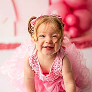 Claire joined the competition — help win amazing prizes! toddler, girl, pink_dress, pigtails, bows, smiling, crawling, balloons, pink_background, child, happy, portrait, cute, indoor, celebration, baby, closeup, playful, dress, person