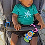 Hiram Treh participe au concours pour gagner de l'argent avec cette photo : toddler, child, stroller, toy, sneakers, clothing, footwear, outdoor, daylight, curious, seat, grip, safety_bar, pavement, casual, person, shorts, shirt, baby_toy, expression