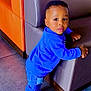 baby, blue_jeans, blue_shoes, blue_sweater, casual_clothing, child, couch, curious, cute, floor_tiles, furniture, happy, home, indoor, leaning, person, portrait, sneakers, toddler, young_child
