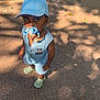 beads, blue_clothing, boy, cap, child, cute, looking_up, mickey_mouse, outdoor, pacifier, pavement, playful, sandals, shadow, shorts, skateboard, summer, sunlight, toddler, toy