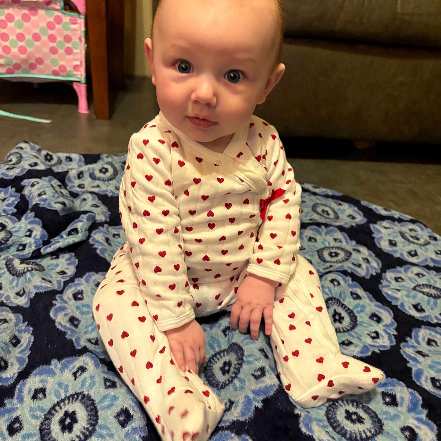 Demi joined the competition — help win amazing prizes! baby, blanket, blue_rug, carpet, child, cozy, cute, eyes, face, floor, hands, heart_pattern, indoor, infant, living_room, onesie, portrait, sitting, sofa, toy_bin