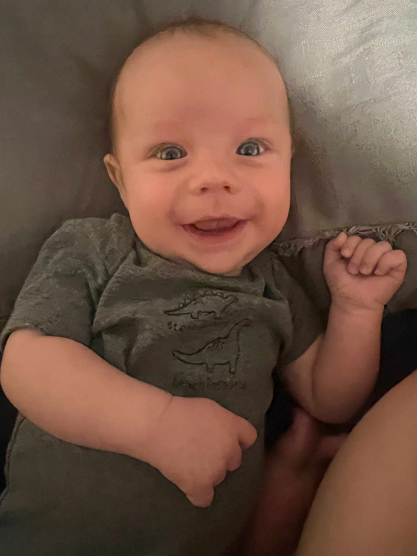 Ozias joined the competition — help win amazing prizes! baby, smiling, infant, face, arm, hand, clothing, dinosaur_print, lying_down, cute, happy, child, portrait, skin, person, expression, indoors, closeup, young, toddler